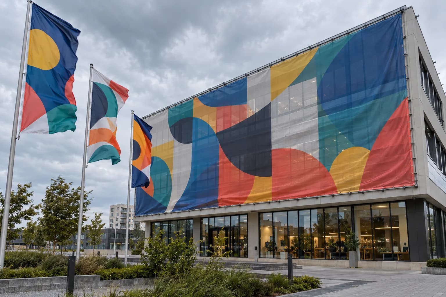 Banner mesh mare cu grafică abstractă pe fațada unei clădiri comerciale, cu steaguri care flutură în vânt